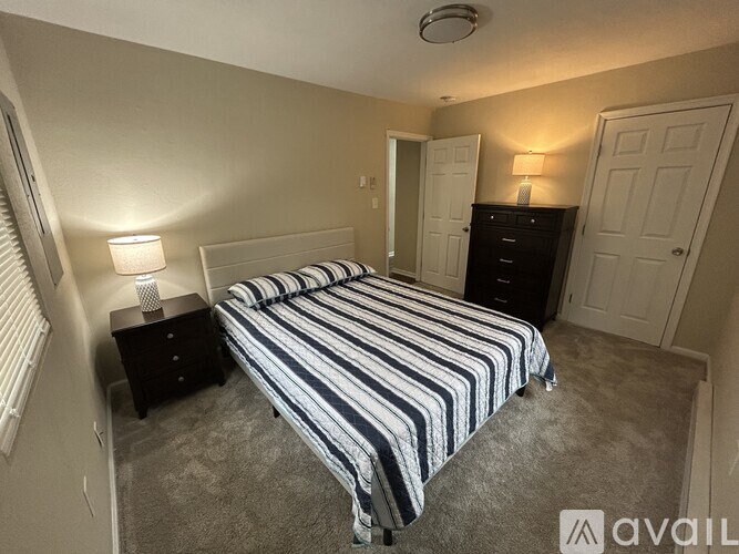 A bedroom with a bed, nightstand, and two lamps.