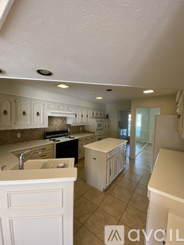 A kitchen with white cabinets and a white fridge.