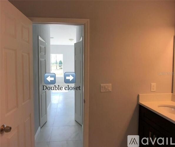 A bathroom with a white door and a mirror on the wall.