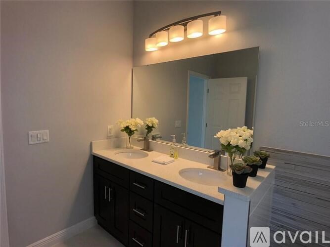 A bathroom with a sink, mirror, and flowers.