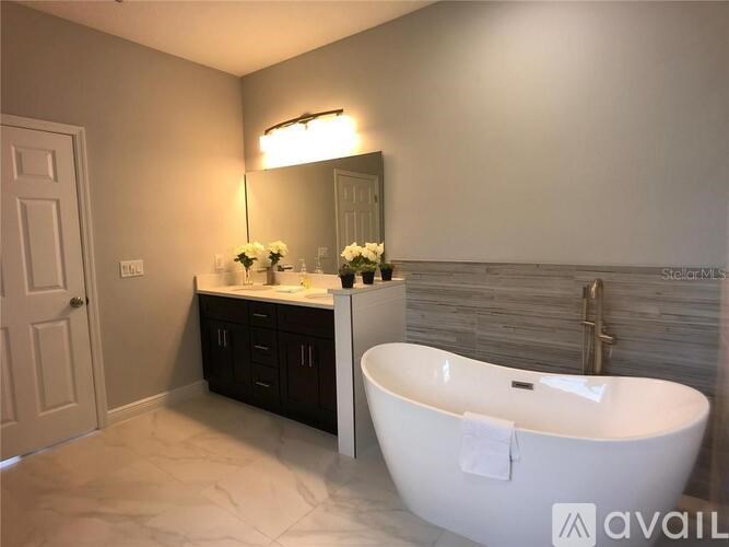 A white bathroom with a tub, sink, and mirror.