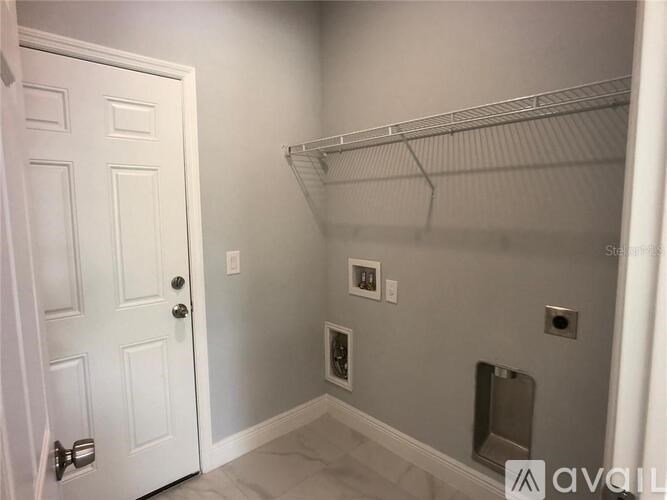 A white door is on the left of a wall with a shelf and a toilet paper holder.