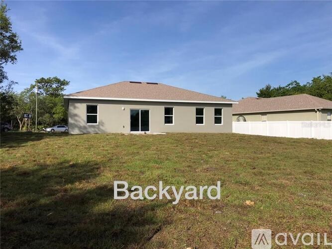 A backyard with a house and a car parked in front.