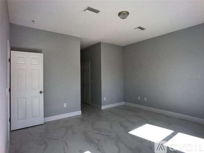 A room with a white door and a window letting in sunlight.