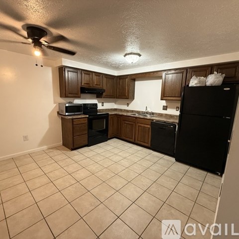 A kitchen with black appliances and wooden cabinets.