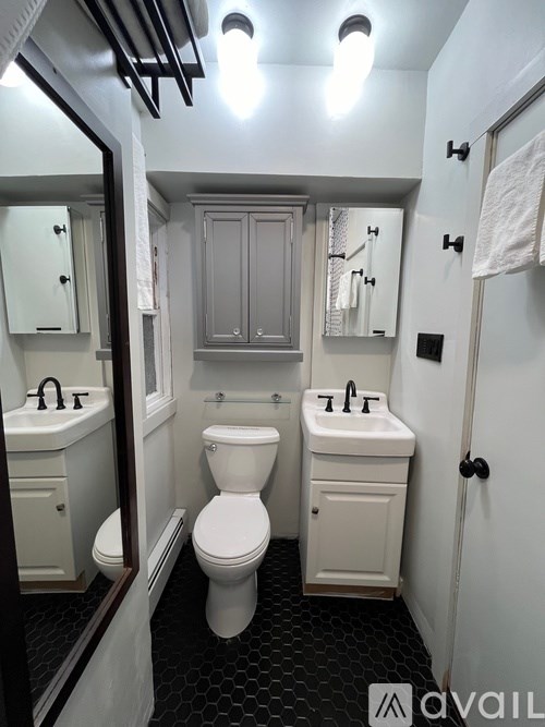 A bathroom with a toilet, sink, and mirror.