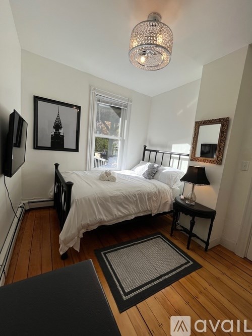 A bedroom with a bed, a lamp, and a chandelier.