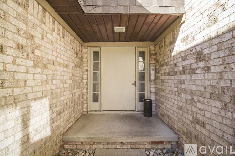 A white door is on the left side of a brick wall.