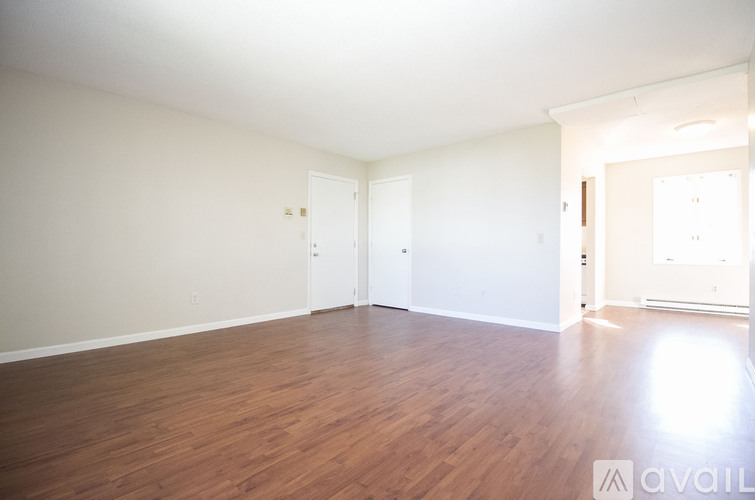 A spacious room with wooden flooring and white walls.