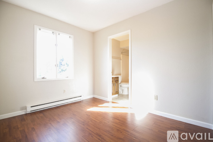 A room with wooden floors and a window with a view of trees outside.