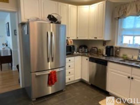 A kitchen with a stainless steel refrigerator and white cabinets.