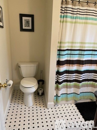 A white toilet in a bathroom with a shower curtain.