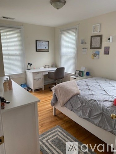 A bedroom with a bed, desk, and chair.