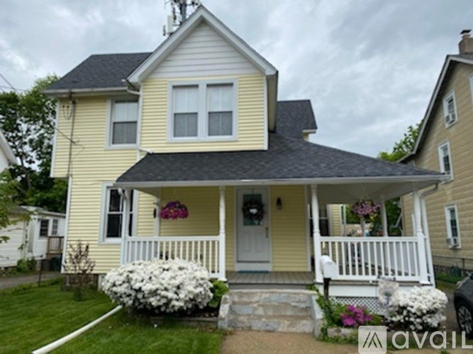 A yellow house with a white porch and a wreath on the door.