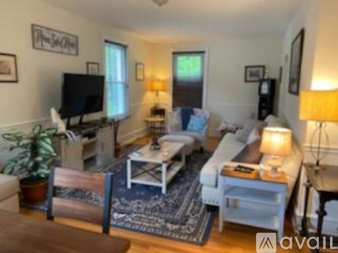 A living room with a white couch, a coffee table, and a television.