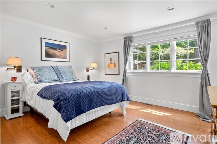 A bedroom with a large bed and a window with curtains.