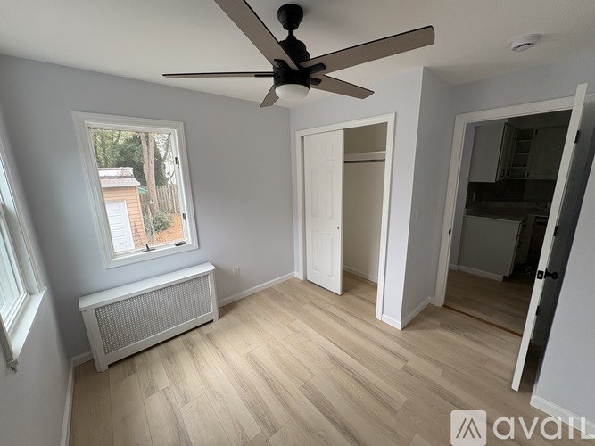 A room with a ceiling fan and a window with a view of a house.