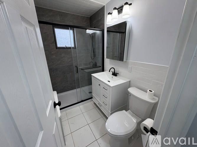 A white toilet sits in a bathroom next to a white cabinet and a white sink.