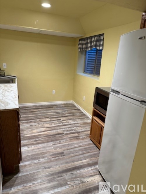 A kitchen with a white refrigerator and wooden flooring.