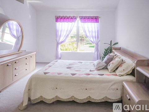 A bedroom with a bed, dresser, and mirror.