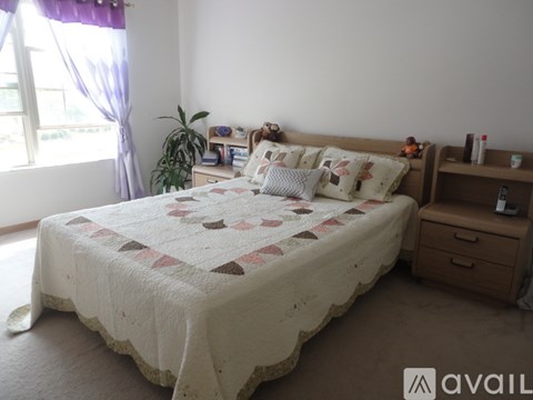 A bedroom with a bed, nightstand, and window.