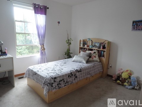 A bedroom with a bed, a window with curtains, a bookshelf, and some toys.