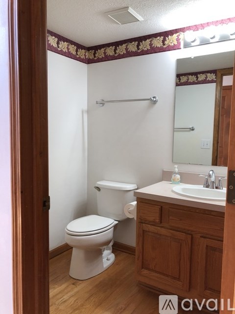 A bathroom with a toilet, sink, and a towel rack.