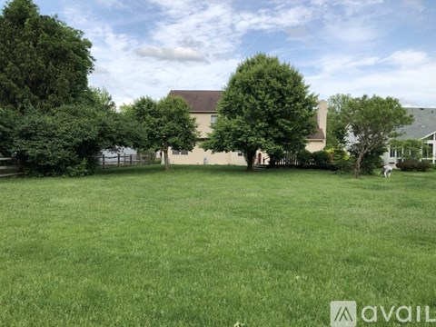 A large grassy field with trees and a building in the background.
