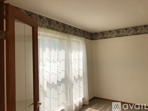 A room with a window covered by a white curtain.