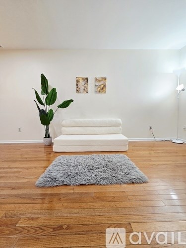 A white sofa sits in a room with wooden floors and a grey rug.