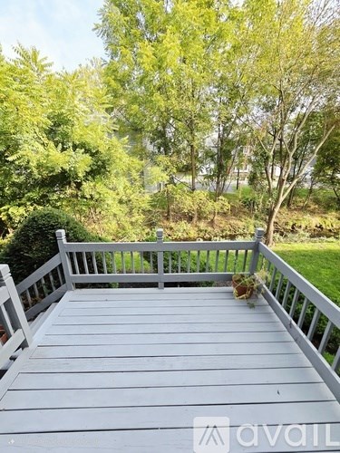 A wooden deck with a railing and a tree in the background.