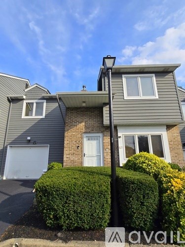A house with a grey facade and a white door is for sale.