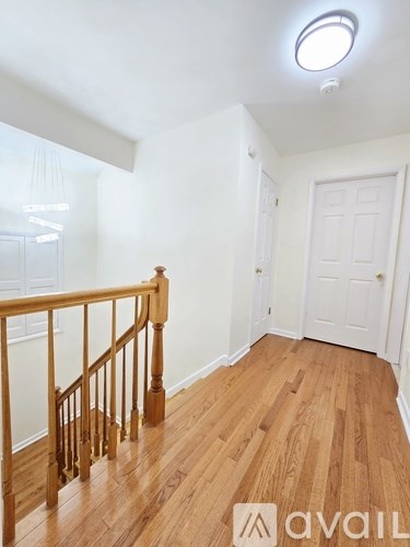 A room with wooden floors and a staircase leading to another room.