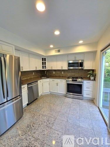 A kitchen with a refrigerator, microwave, oven, and sink.