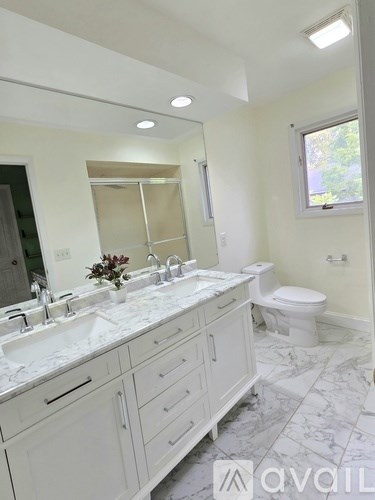 A bathroom with a marble countertop and white cabinets.
