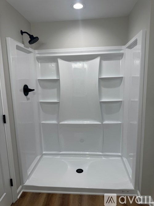 A white walk-in shower with a bench seat and a door.