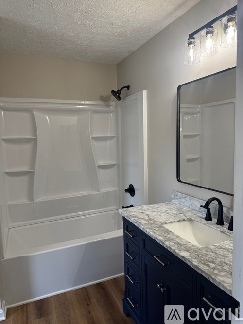 A bathroom with a white tub, sink, and mirror.