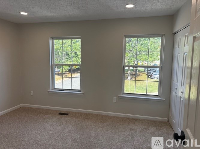 A room with two windows and carpeted floor.