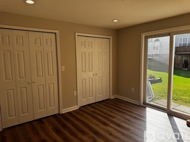 A room with wooden floors and three doors.