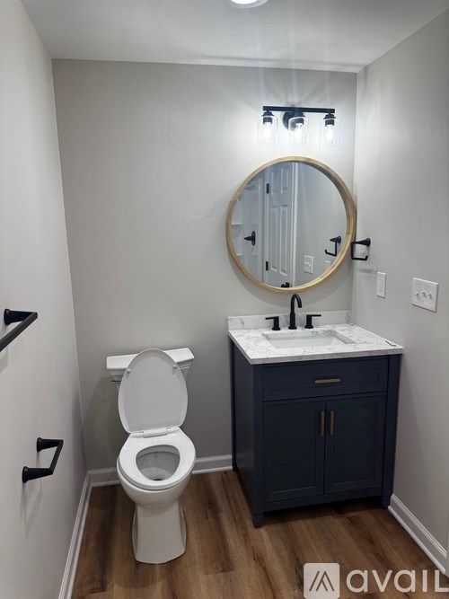 A bathroom with a toilet, sink and mirror.