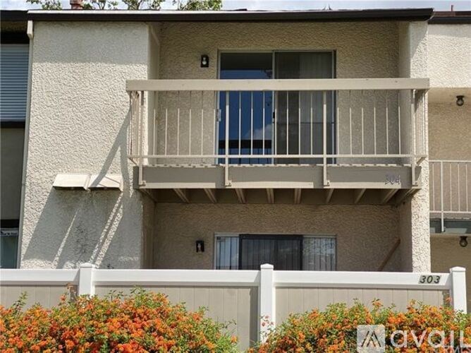 A two-story apartment building with a balcony and a white fence.