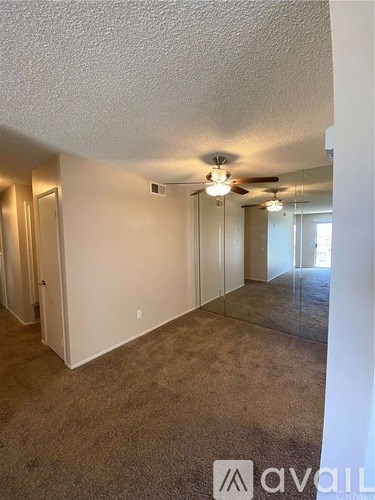 A room with a carpeted floor and a ceiling fan.