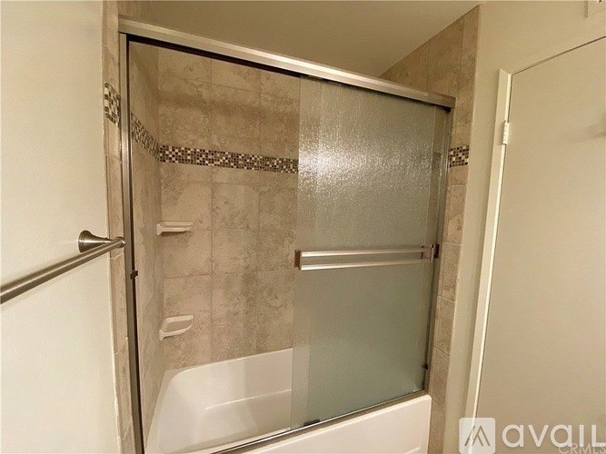 A shower area with a glass door and a white tub.