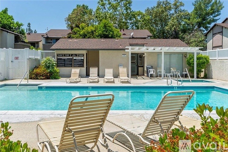 A poolside area with chairs and a house in the background.