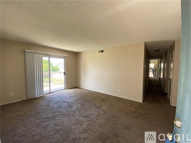 A room with carpeted floor and a sliding glass door leading outside.