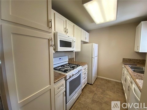 A kitchen with white cabinets and appliances.