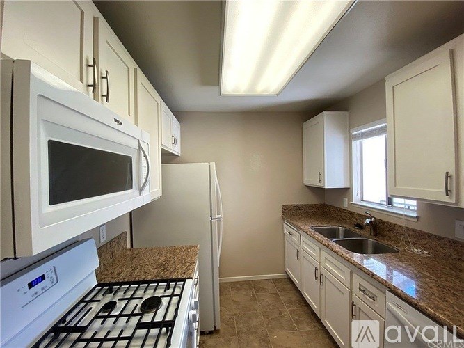 A kitchen with white appliances and cabinets.