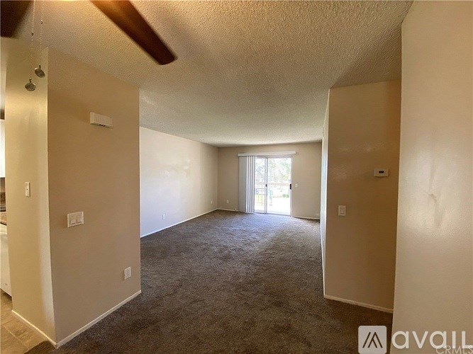 A spacious living room with a carpeted floor and a ceiling fan.