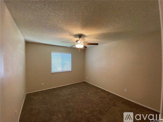A room with a ceiling fan and a window with blinds.