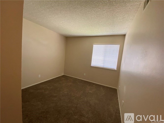 A room with a carpeted floor and a window with blinds.